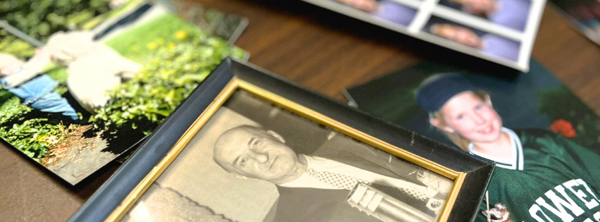 A close-up image of family photographs from different eras, scattered on a table.